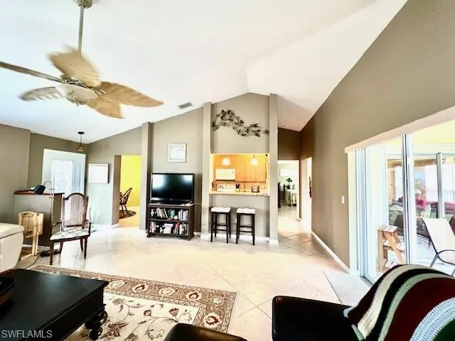 Living room with ceiling fan, vaulted ceiling, and light tile patterned floors