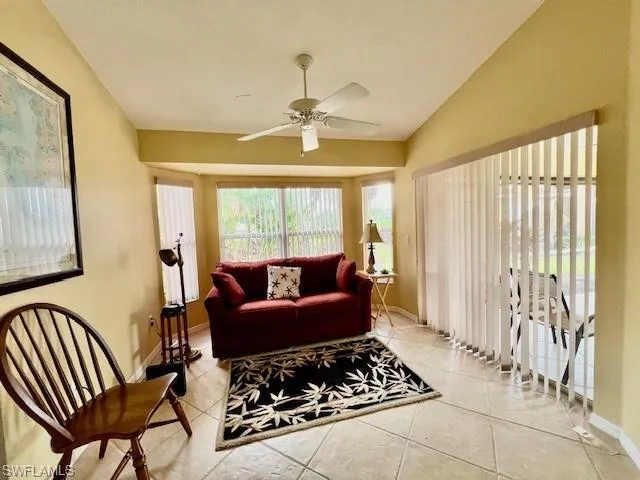 Tiled living room with lofted ceiling and ceiling fan
