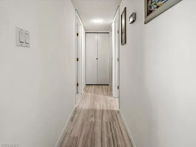 Corridor featuring light wood-type flooring and a textured ceiling