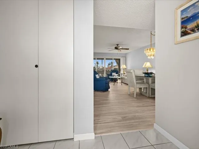 Corridor with light hardwood / wood-style flooring, a textured ceiling, and a notable chandelier