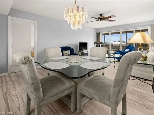 Dining area with ceiling fan with notable chandelier and light hardwood / wood-style flooring