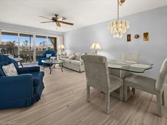 Dining area featuring a textured ceiling, light hardwood / wood-style flooring, and ceiling fan with notable chandelier