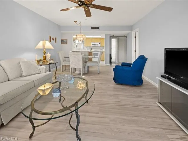 Living room featuring ceiling fan with notable chandelier and light hardwood / wood-style flooring