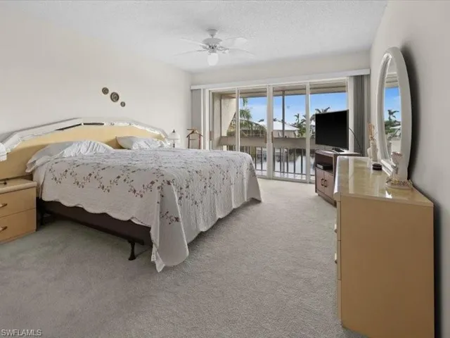 Bedroom featuring access to exterior, a textured ceiling, light colored carpet, and ceiling fan