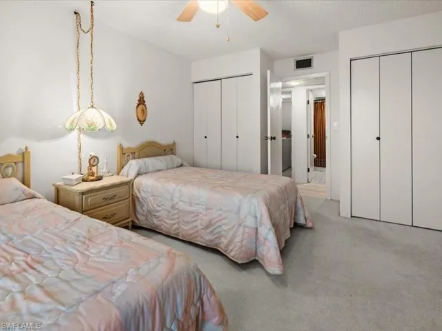 Carpeted bedroom featuring ceiling fan and two closets