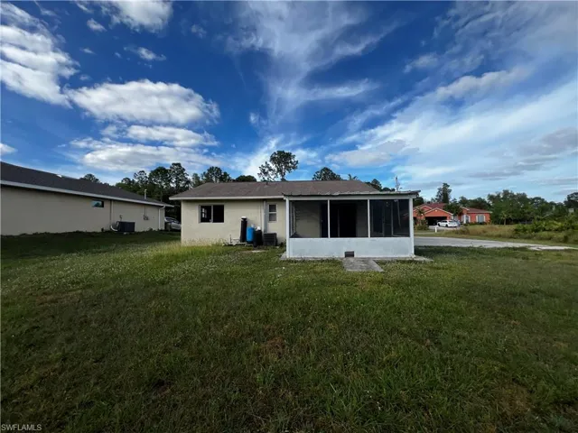 Back of house with a sunroom, cooling unit, and a yard