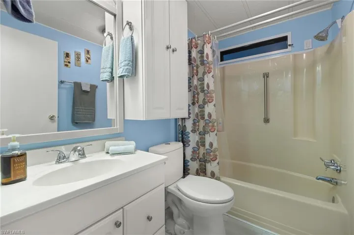 Full bathroom with vanity, shower / bath combination with curtain, and toilet