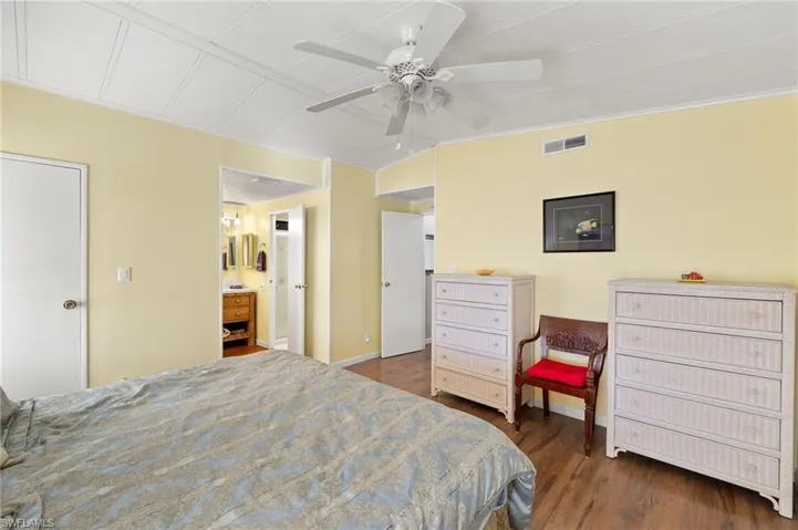 Bedroom with dark hardwood / wood-style flooring, ensuite bathroom, and ceiling fan