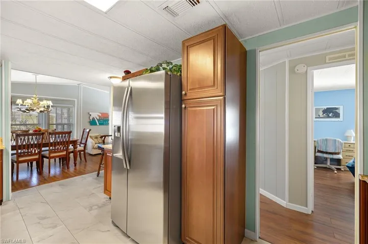 Kitchen with crown molding, decorative light fixtures, light hardwood / wood-style flooring, a notable chandelier, and stainless steel fridge with ice dispenser