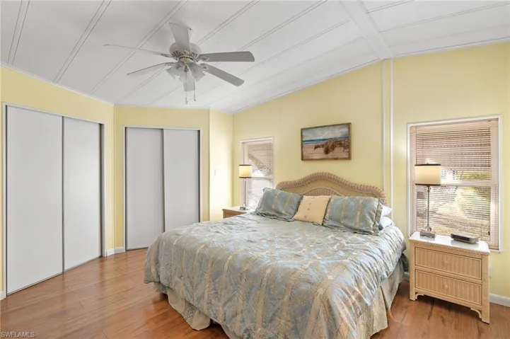 Bedroom featuring hardwood / wood-style flooring, ceiling fan, vaulted ceiling, and two closets