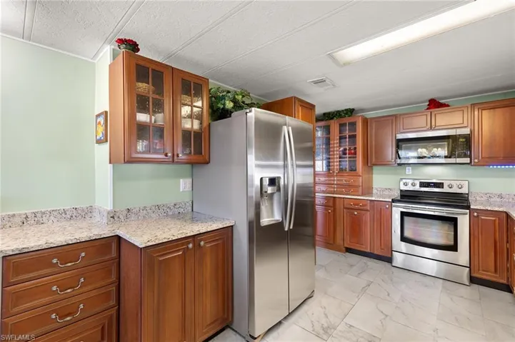 Kitchen featuring appliances with stainless steel finishes and light stone counters