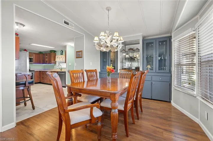 Dining space featuring sink, ornamental molding, a chandelier, and hardwood / wood-style flooring