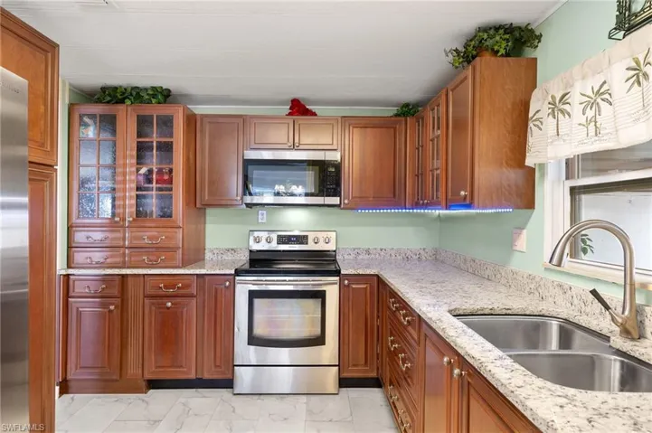 Kitchen with light stone counters, sink, and stainless steel appliances