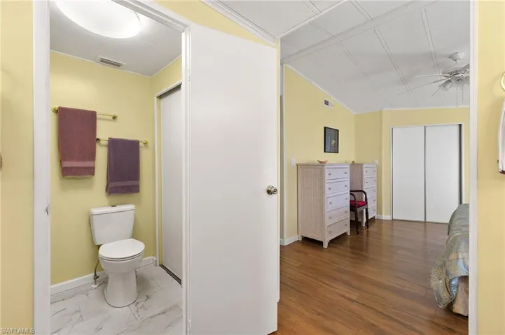 Bathroom featuring toilet, hardwood / wood-style floors, vaulted ceiling, and ceiling fan