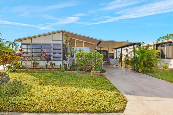 View of front of property with a front yard and a carport