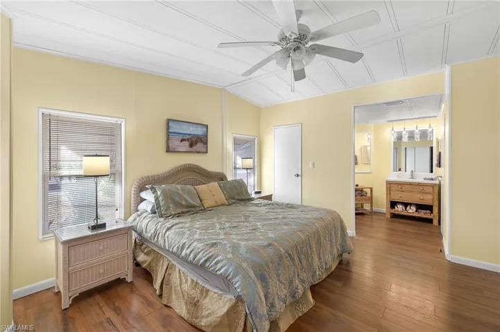 Bedroom with ceiling fan, lofted ceiling, dark wood-type flooring, and multiple windows