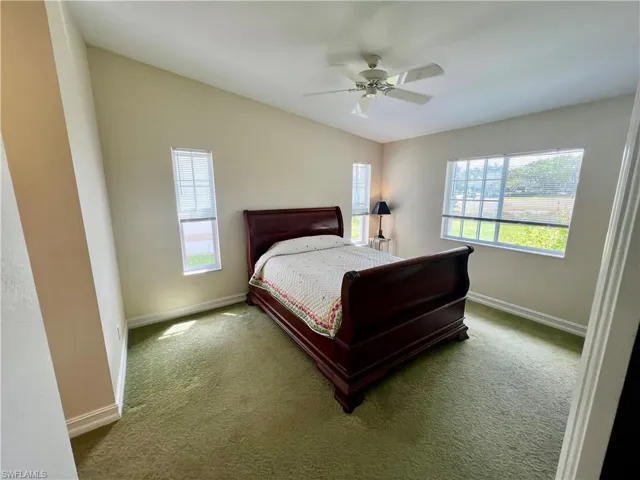 Bedroom with ceiling fan, baseboards, lofted ceiling, and carpet flooring