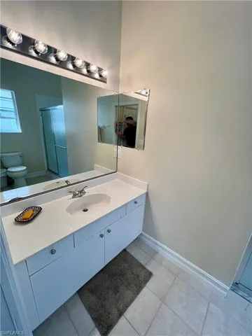 Bathroom featuring vanity, baseboards, toilet, an enclosed shower, and tile patterned flooring
