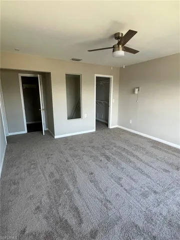 Carpeted spare room with baseboards, ceiling fan, and visible vents
