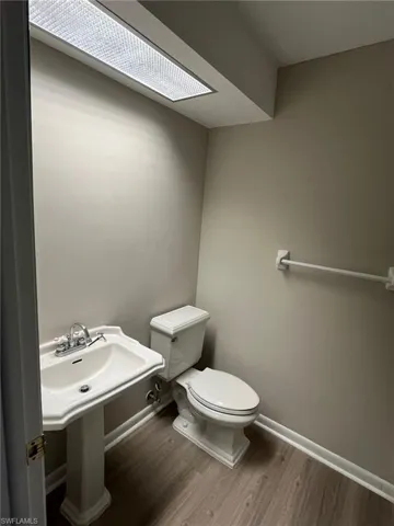 Half bath featuring baseboards, toilet, and wood finished floors