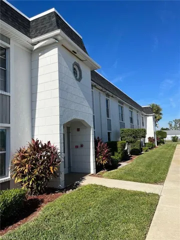 View of home's exterior featuring a lawn, a shingled roof, and mansard roof