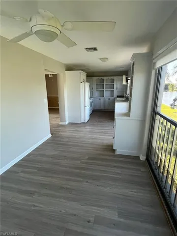 Hallway featuring a sink, baseboards, visible vents, and dark wood-type flooring