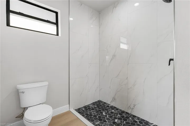 Full bathroom featuring a marble finish shower and wood finished floors