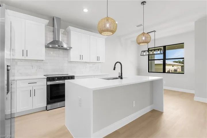 Kitchen featuring wall chimney exhaust hood, electric stove, backsplash, light wood-style flooring, and light countertops