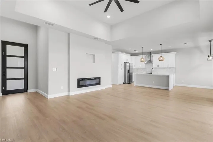 Unfurnished living room featuring ceiling fan, recessed lighting, light wood-style floors, and a glass covered fireplace