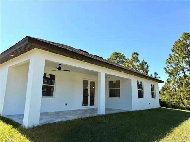 Rear view of property with a lawn, stucco siding, a patio area, and a ceiling fan