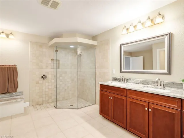 Bathroom featuring double vanity, a walk in shower, and light tile patterned floors