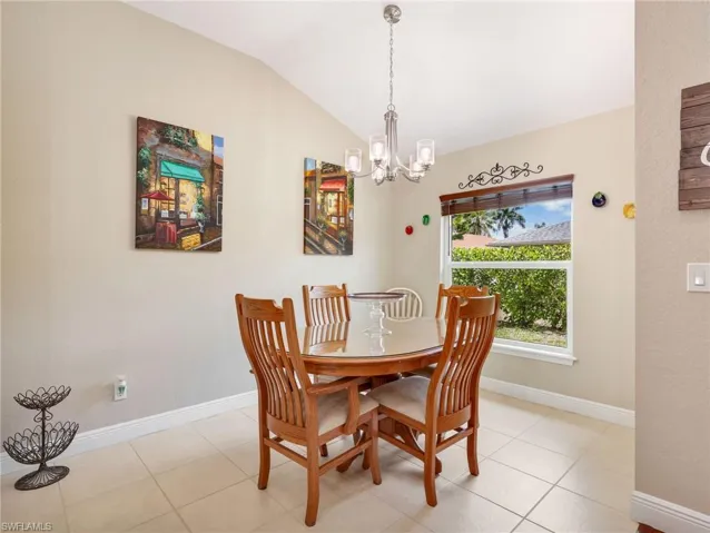 Dining space with vaulted ceiling, hanging lights, and light tile patterned floors