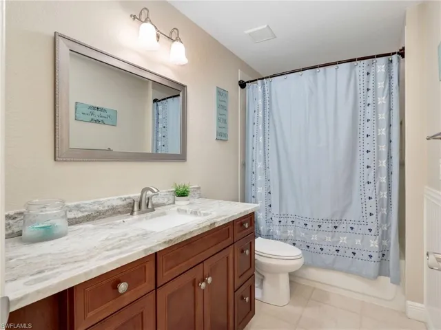 Full bathroom with vanity, shower / bath combination with curtain, and light tile patterned floors