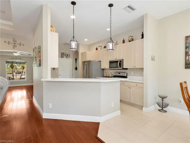 Kitchen with light countertops, a peninsula, stainless steel appliances, pendant lighting, and cream cabinetry