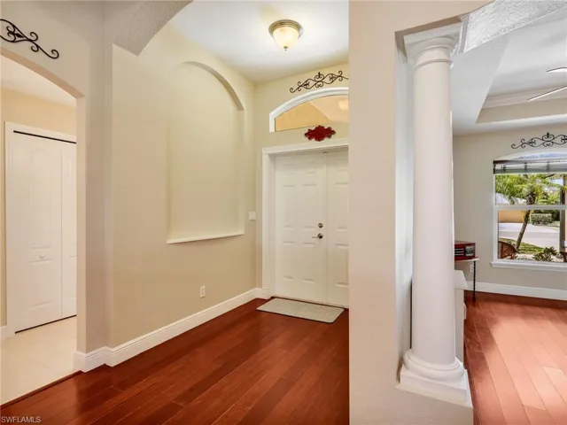 Entrance foyer with dark wood-style flooring, arched walkways, and ornate columns
