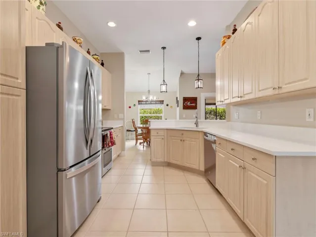 Kitchen featuring stainless steel appliances, a peninsula, light countertops, hanging light fixtures, and light tile patterned floors