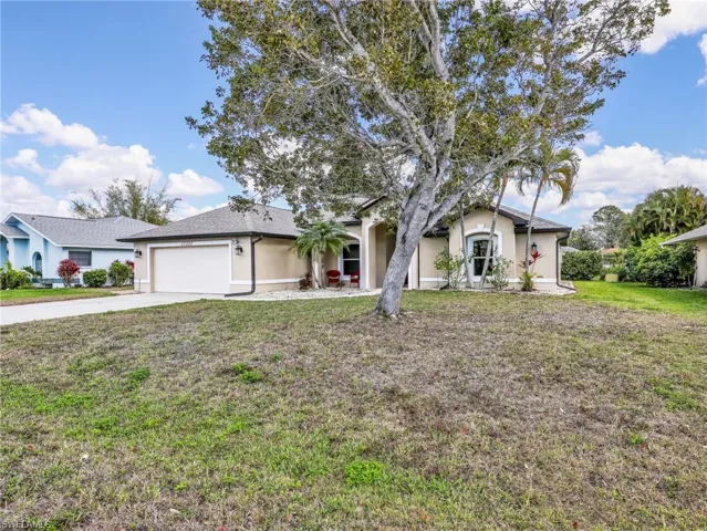 Single story home featuring a front yard, a garage, stucco siding, and driveway
