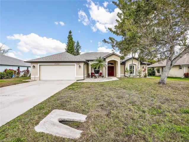 Ranch-style house with a garage, concrete driveway, stucco siding, and a front lawn