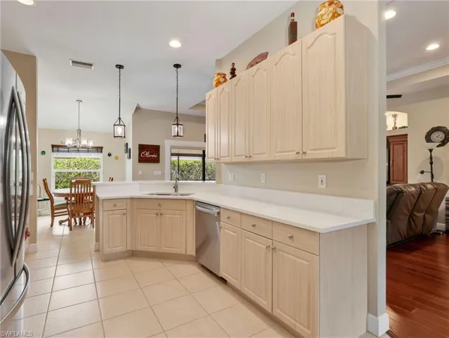 Kitchen with stainless steel appliances, light countertops, light wood finish cabinetry, a peninsula, and a chandelier