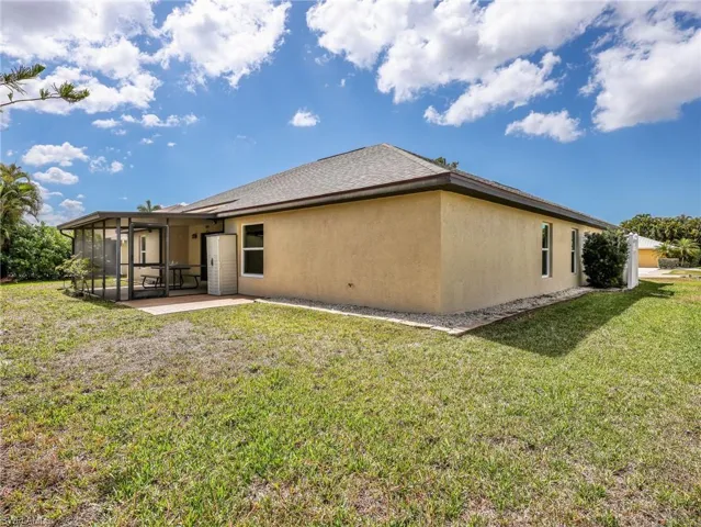 Rear view of property with a lawn, stucco siding, and a sunroom