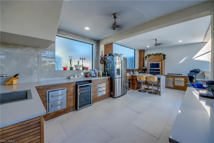 Kitchen with brown cabinets, wine cooler, appliances with stainless steel finishes, a breakfast bar area, and recessed lighting