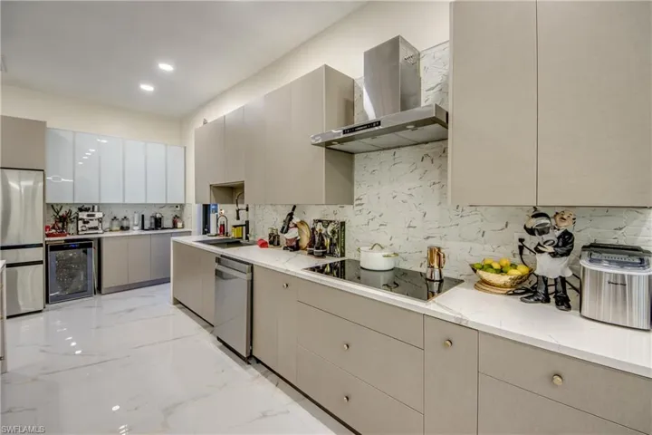 Kitchen featuring beverage cooler, wall chimney range hood, stainless steel appliances, gray cabinets, and modern cabinets
