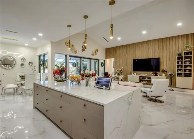 Kitchen featuring pendant lighting, an accent wall, modern cabinets, recessed lighting, and light stone counters