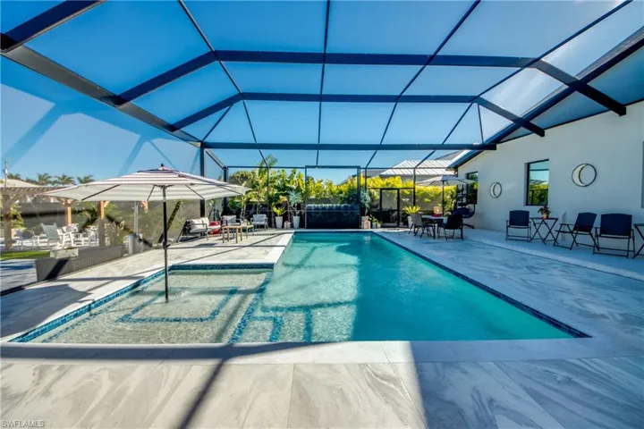 Swimming pool with a patio area, glass enclosure, and a sunroom