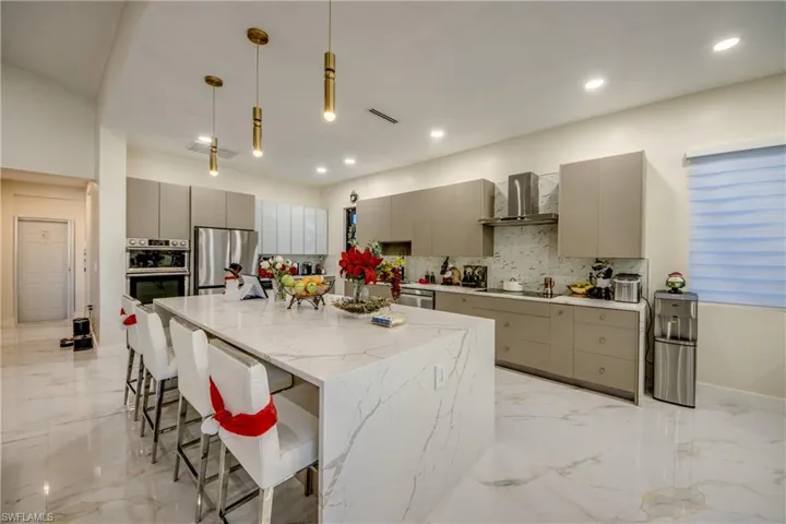 Kitchen featuring gray cabinets, a breakfast bar, a center island, pendant lighting, and stainless steel appliances