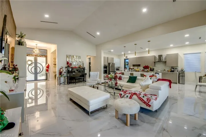 Living area with vaulted ceiling, light marble finish floors, and recessed lighting