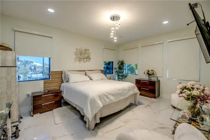 Bedroom featuring light marble finish floors, recessed lighting, and multiple windows