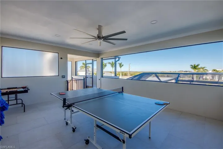 Rec room with ceiling fan, crown molding, and tile patterned floors