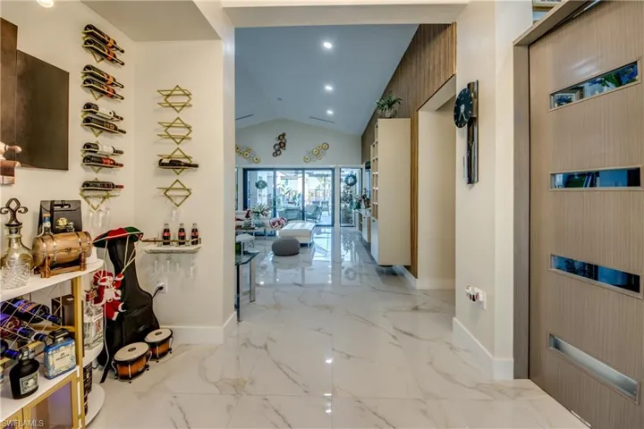 Hallway with lofted ceiling, light marble finish flooring, and recessed lighting