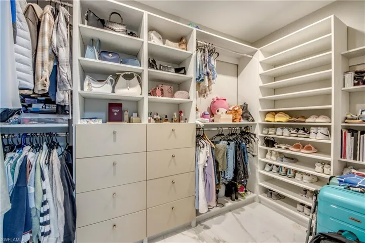 Walk in closet featuring light marble finish flooring